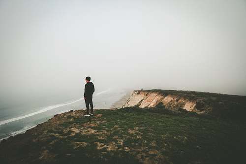 solitude man standing on cliff coast