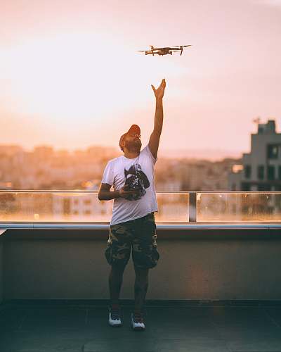 apparel man in white crew-neck t-shirt standing near railings shorts