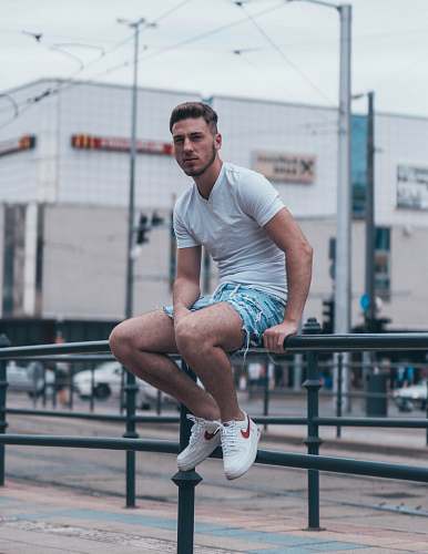 shorts man sits on metal railings apparel