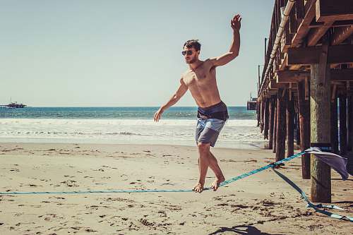 apparel man wearing sunglasses and board shorts standing on rope shorts