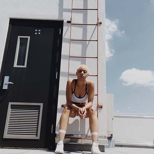 apparel woman in white and black sports bra sitting on orange metal fire ladder home decor