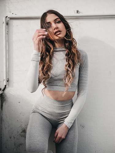 apparel woman wearing grey long-sleeved top leaning on wall sleeve