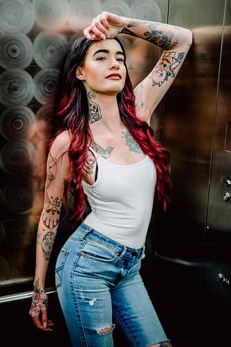 skin woman wearing white spaghetti strap top and distressed blue denim bottoms denim