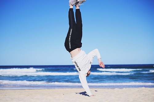 sport man doing cartwheel on sand fitness