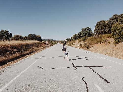 road person tumbling on gray concrete road handstands