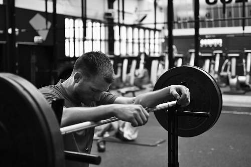 gym gray scale photo of man sitting on bench press black-and-white