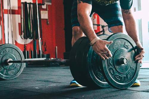 gym man placing weight plate on barbell weights