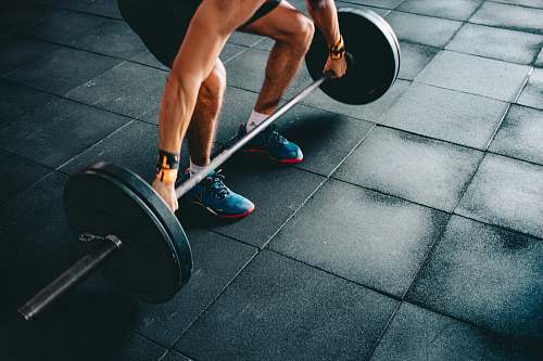 gym person holding black barbell footwear