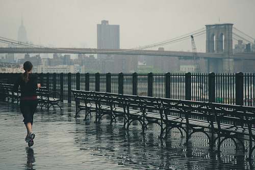 sport woman running near the body of water with Brooklyn Bridge in the background jogging