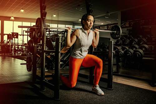 exercise woman wearing gray shirt and orange leggings working out