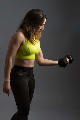human woman wearing pink sports bra holding dumbbells person