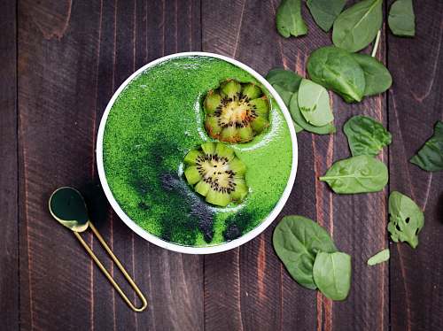 green green liquid in white ceramic container with brass-colored spoon on brown wooden surface vegetable