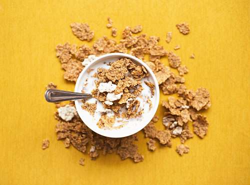 yellow top view of corn flakes in bowl with milk and silver spoon cereal
