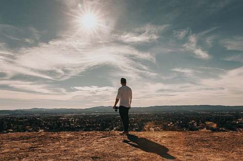 mountain man standing overlooking concrete buildings from behind