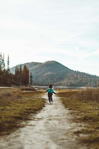 person baby walking on footpath during daytime plant