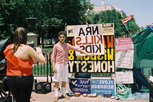 person boy in pink dress shirt standing beside posters apparel