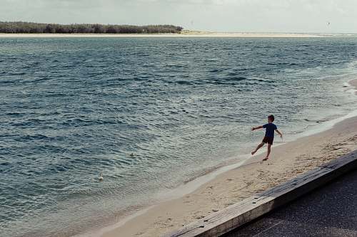 person boy playing beside seashore ocean