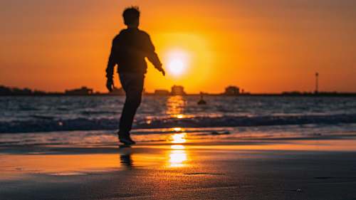 person boy walking at the beach during golden hour nature