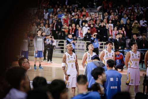 person four basketball players forming a line while standing on court surrounded by crowd people
