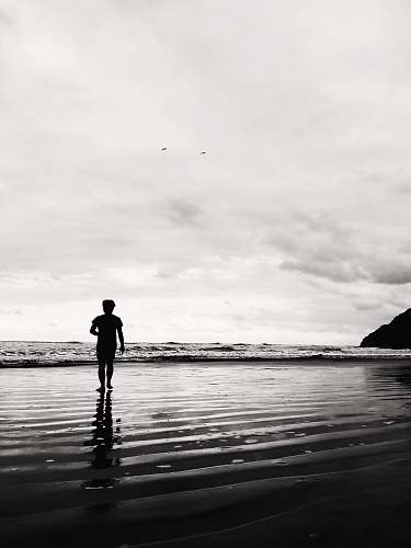 person grayscale photo of man on shore black-and-white