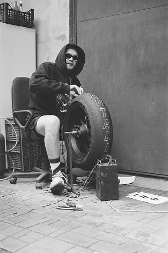 person grayscale photo of man sitting on chair wearing pullover black-and-white