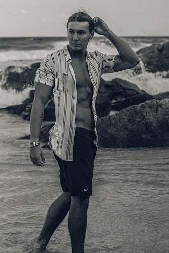 clothing grayscale photo of man standing on seashore apparel