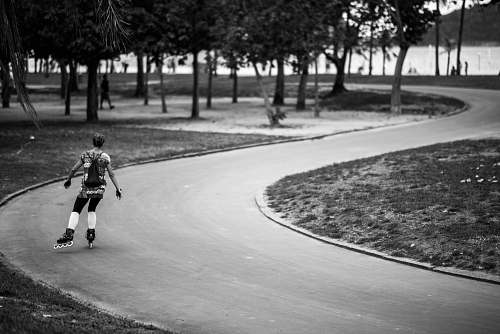 person grayscale photography of girl in inline skates on road black-and-white