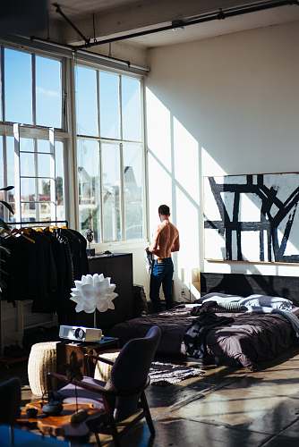person half naked man stands in front of glass window chair