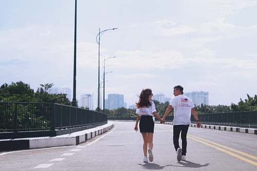 person man and woman holding hands while walking on street apparel