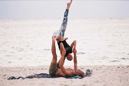 person man and woman making stunt near seashore acrobatic