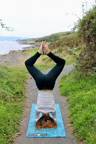 person man doing headstand on teal textile on pathway on island working out