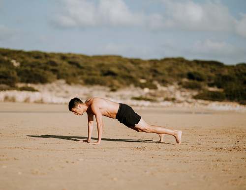person man doing push up on sand people