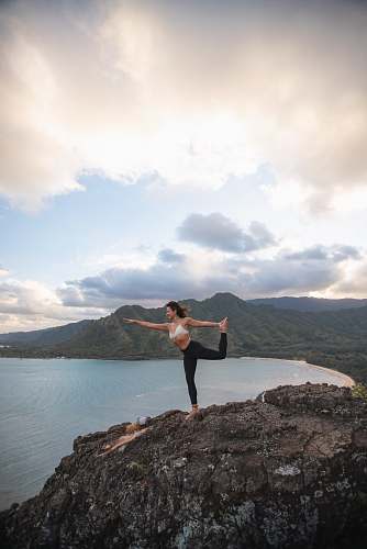person man doing yoga on rock formation outdoors