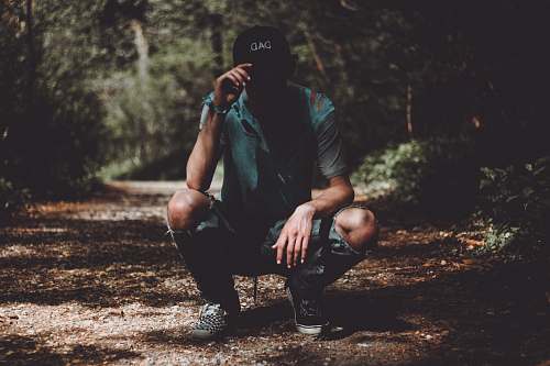 person man holding cap at the pathway near trees people