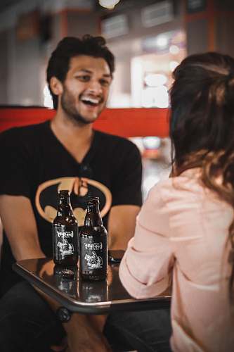 person man in black Batman t-shirt sitting near table with bottles alcohol