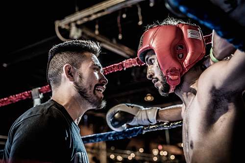 person man in black talking to boxer inside ring people