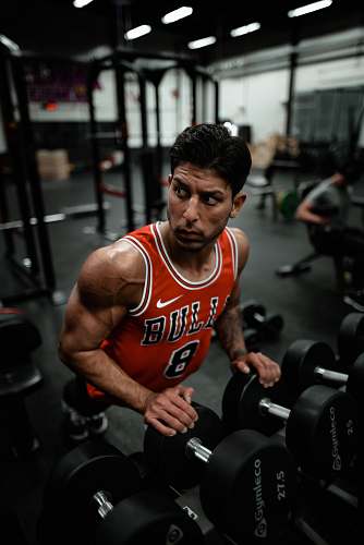 person man in red Chicago Bulls jersey doing push-up exercise on dumbbells sports
