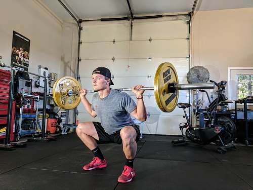 person man lifting barbell on back inside gym exercise