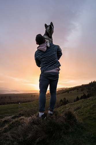 person man lifting dog during sunset nature
