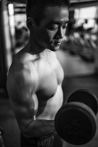 person man lifting dumbbell inside gym black-and-white