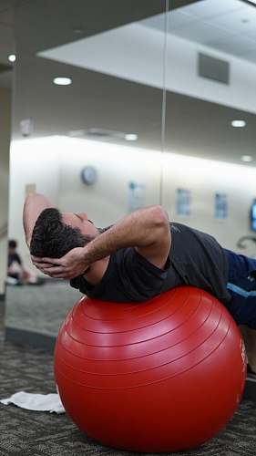 person man lying on red stability ball fitness