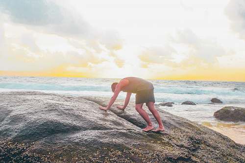 person man on gray rock near body of water water