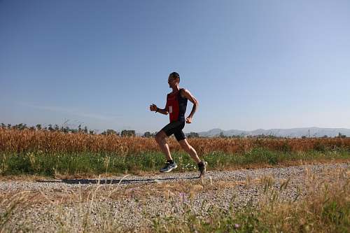 person man red and black top running on farm road sport