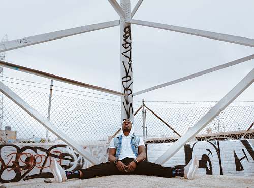 person man sitting beside white metal stand outdoors