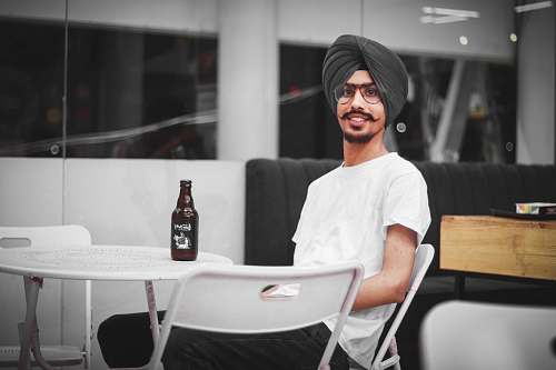 person man sitting on chair near table with bottle of beer sitting