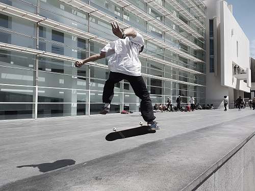 person man skateboarding beside building during daytime people