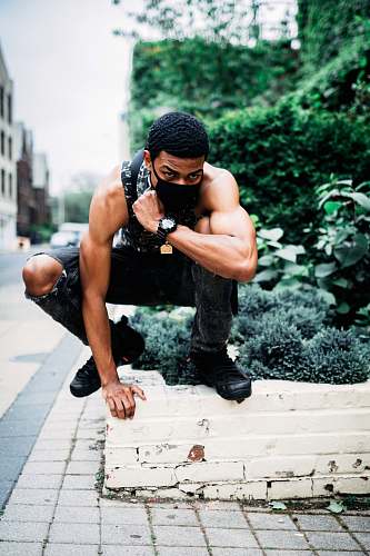 person man squatting on concrete wall apparel