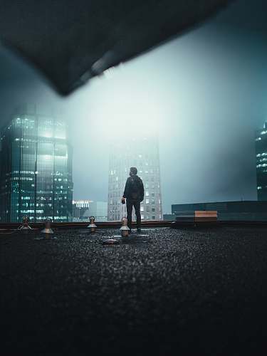 person man standing on roof top at night asphalt