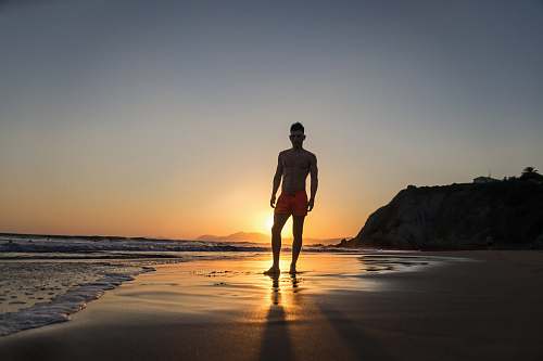 person man standing on shore with sunset background on the horizon standing