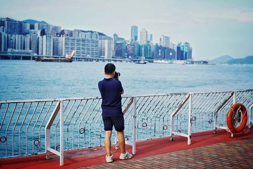 person man taking photo of city buildings people